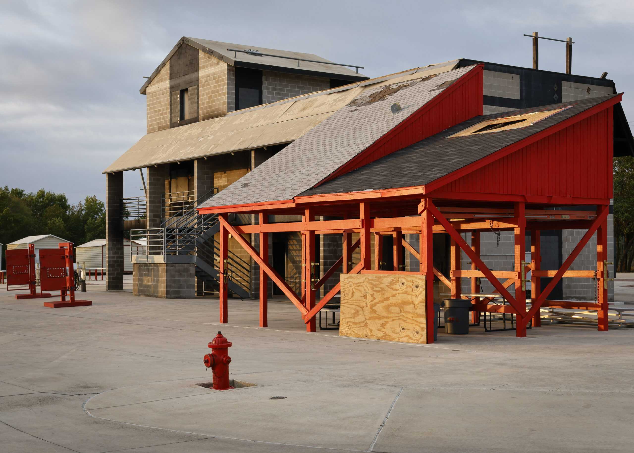 Training structures at the Fire Academy support training in extraction and extinguishing. The building on the left gets set on fire, and the students learn how to safely maneuver through it. The red structure on the right is used to teach the students how to extract patients from a roof. Photo by Natalia Edwards.