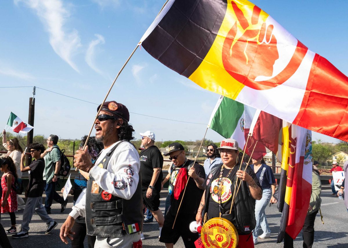 Member of The Brown Berets Juan Aguirre waves a flag at the César E. Chávez March for Justice March 21. Photo by Jacob Lopez.