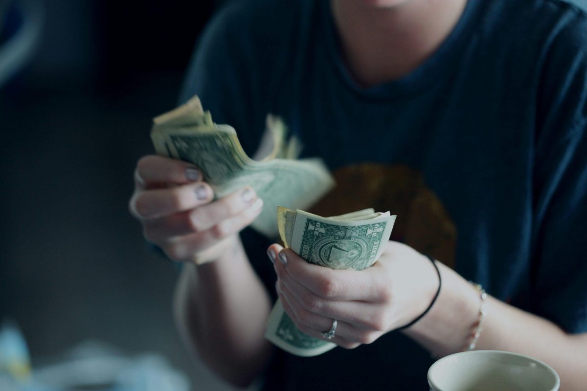 A photo of a person counting dollar bills